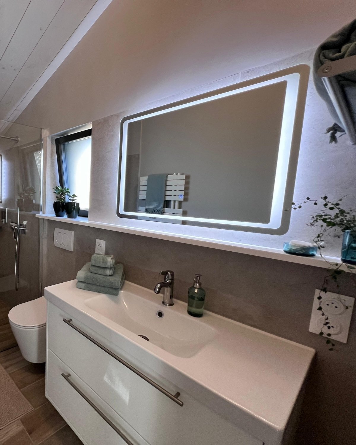 Lavabo moderne et miroir lumineux dans la salle de bain de la suite ONNO II à L’Épine sur l’île de Noirmoutier