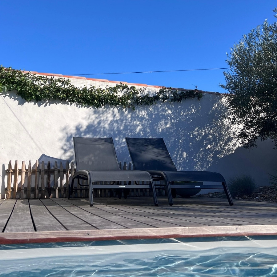 Transats au bord de la piscine chauffée dans le jardin à Noirmoutier